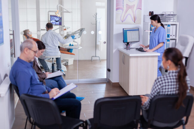 Crowded stomatology waiting area with people filling form dental office supplies purchasing group